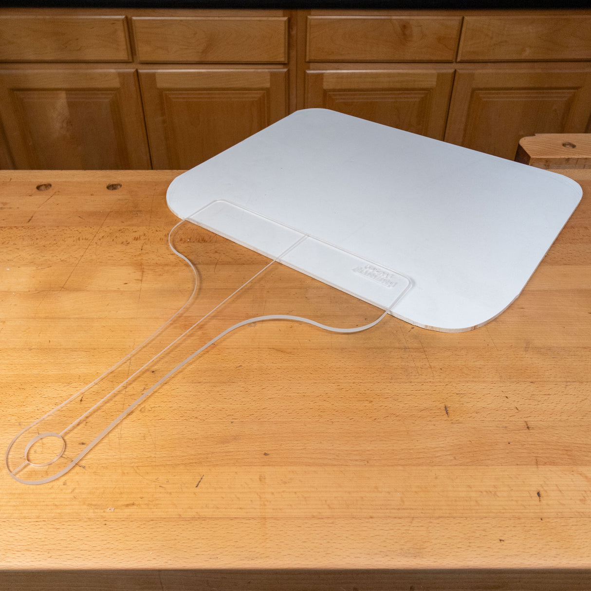 Clear acrylic cutting board template with handle on wood workbench in workshop