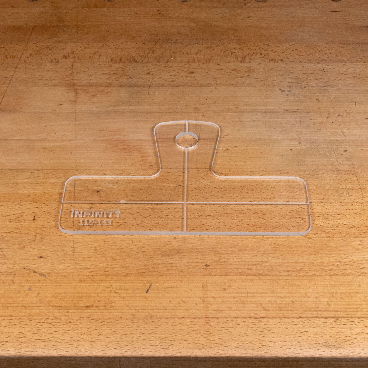 Clear acrylic handle template with etched guidelines on a wooden workbench.