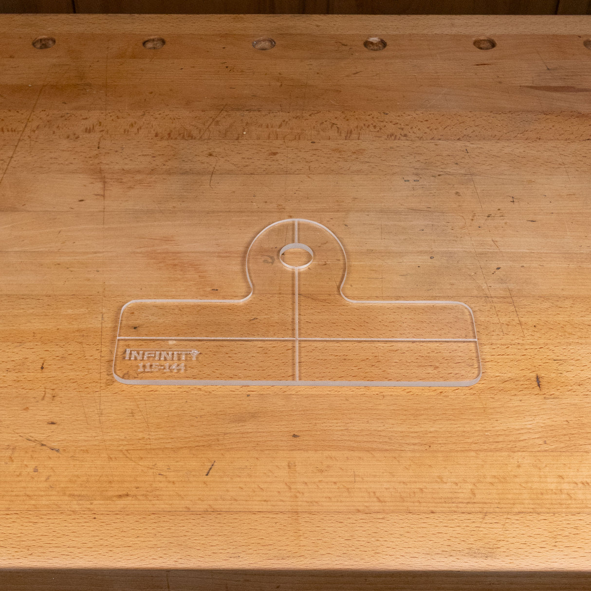 Clear acrylic handle template with engraved guidelines on a woodworking bench