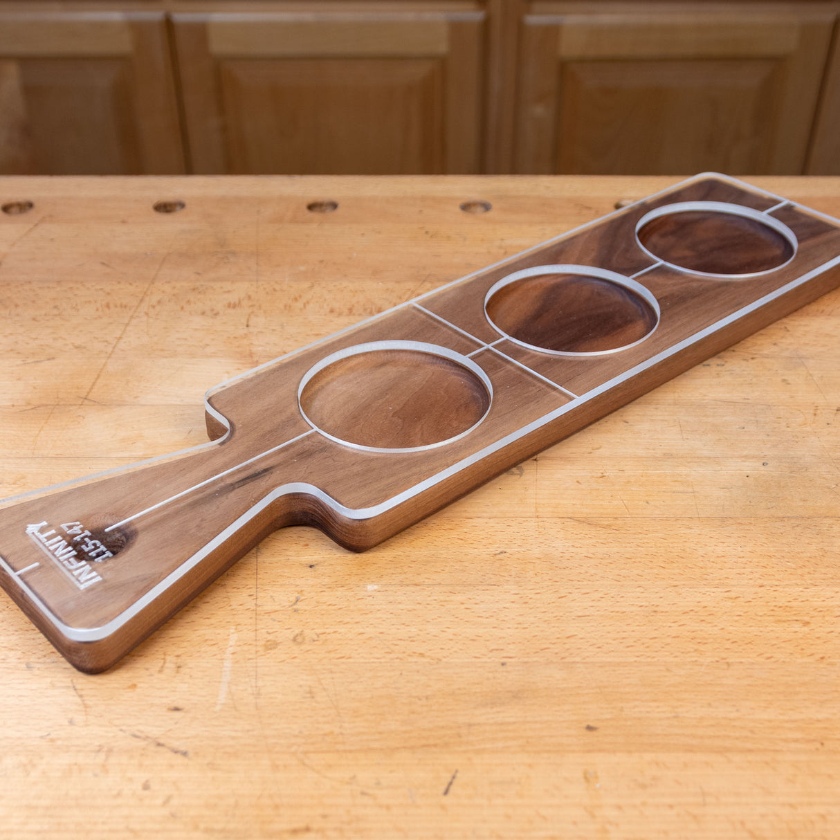 Acrylic cutting board template overlay on wooden paddle board with circular cutouts on a workbench