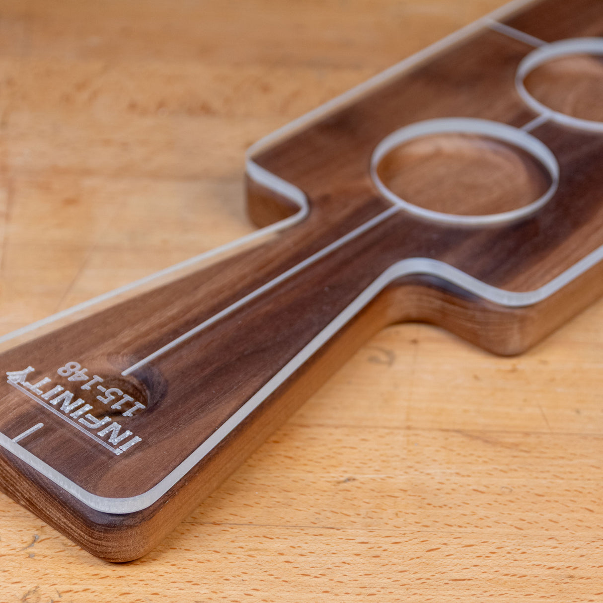 Acrylic cutting board template with labeled handle and round cutouts on a wood surface