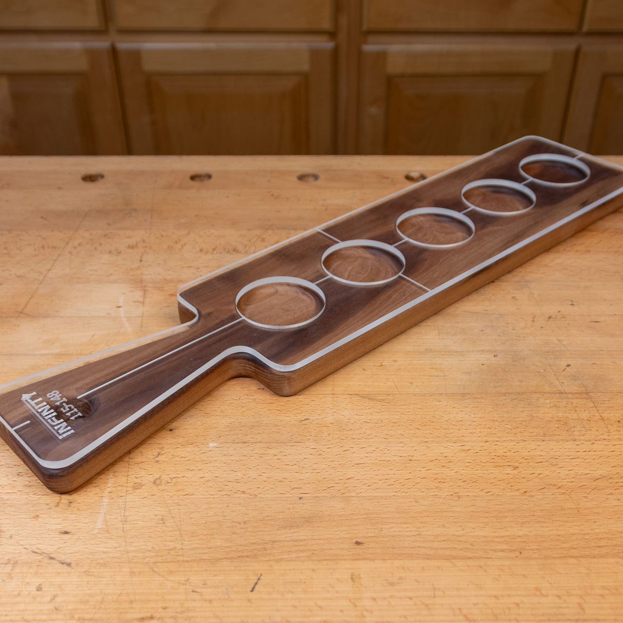 Rectangular acrylic cutting board template overlay with five circular cutouts on a wood workbench