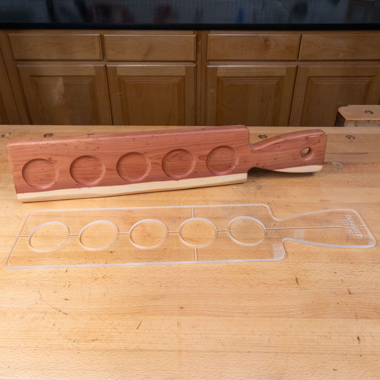 Clear acrylic cutting board template with circle cutouts on a wood workshop bench