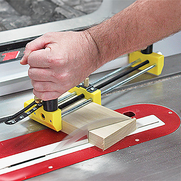 Woodworker using a table saw with a yellow safety push block guide to cut lumber