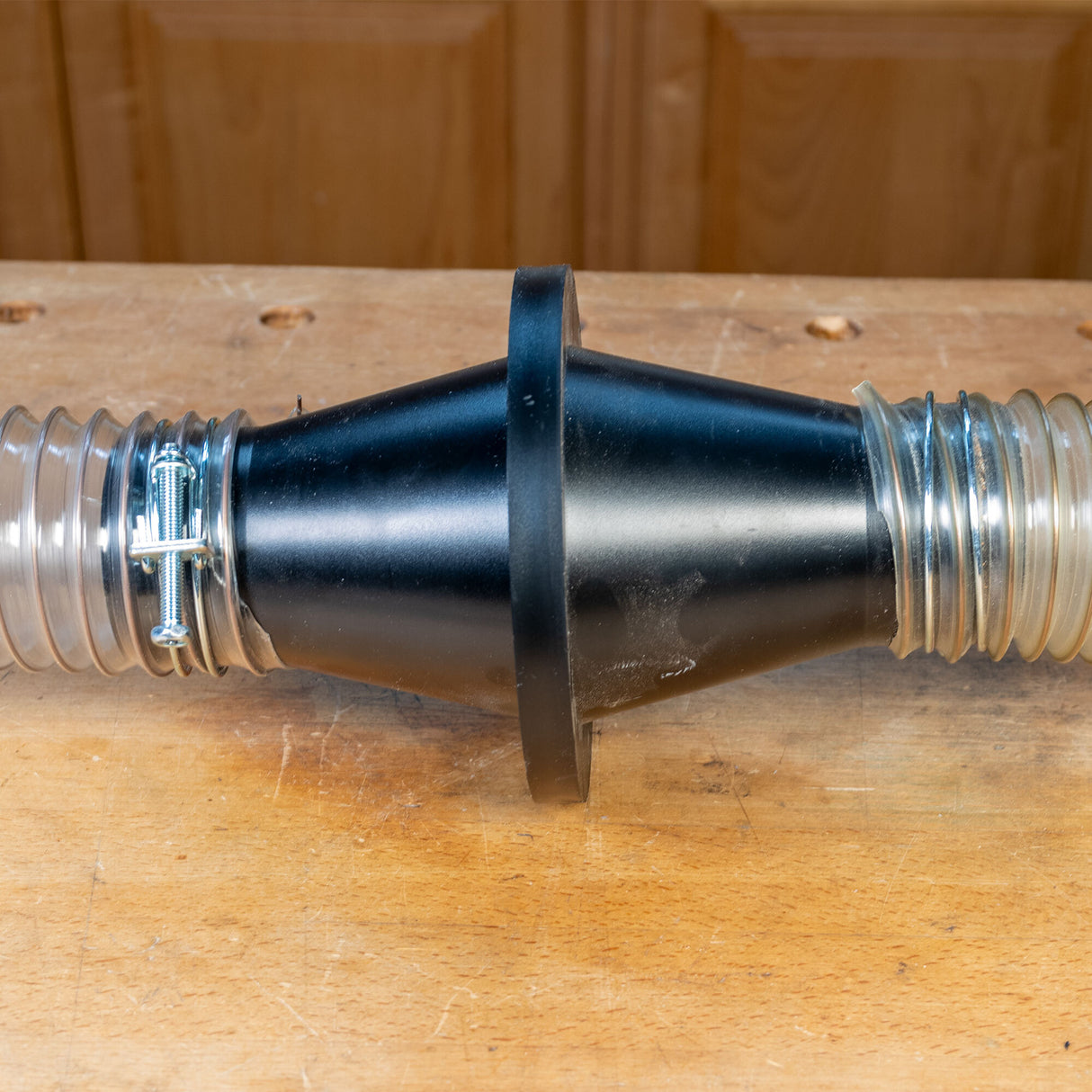 Dust collection hose connector with clamps on a woodworking bench