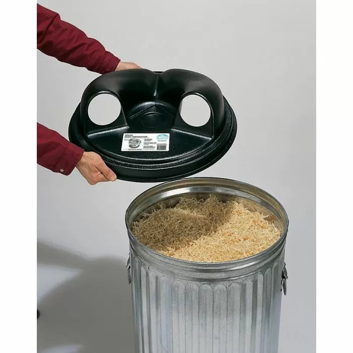 Hands holding dust separator lid above metal trash can filled with wood shavings