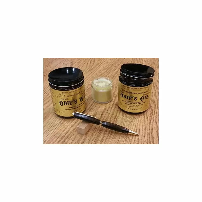 Wood finish jars, small container, and dark wood pen on a wood surface for woodworking projects.