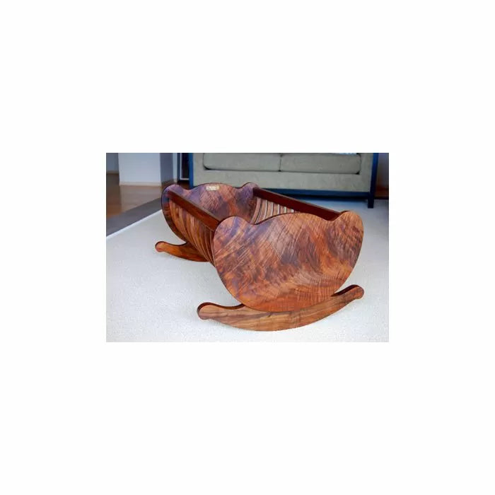 Handcrafted wooden rocking cradle with curved sides on a light carpet