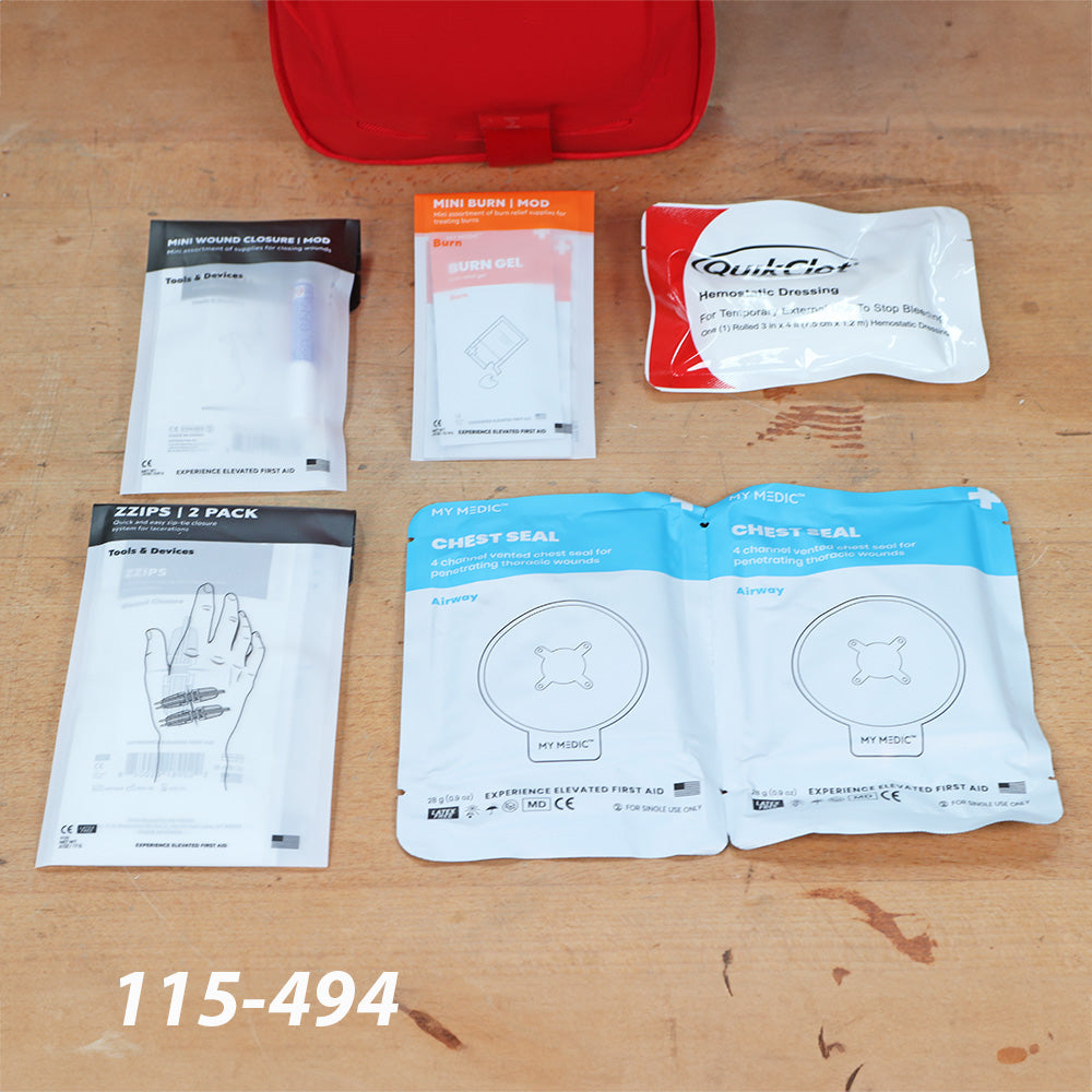 First aid kit supplies including wound closure strips, burn gel, hemostatic dressing, chest seals, and zippers displayed on a workbench.