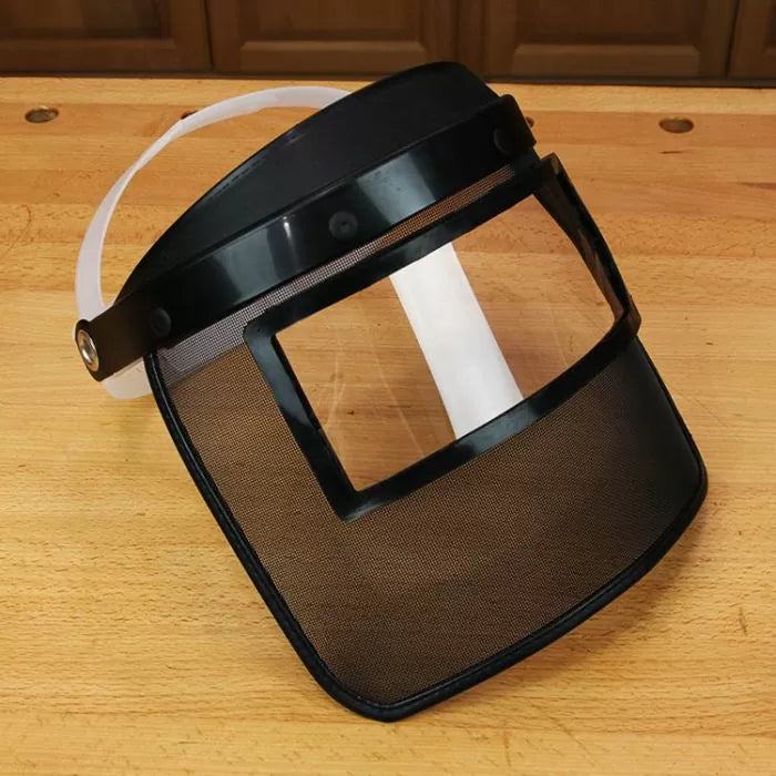 Woodworking mesh face shield with clear window on a workbench for workshop safety