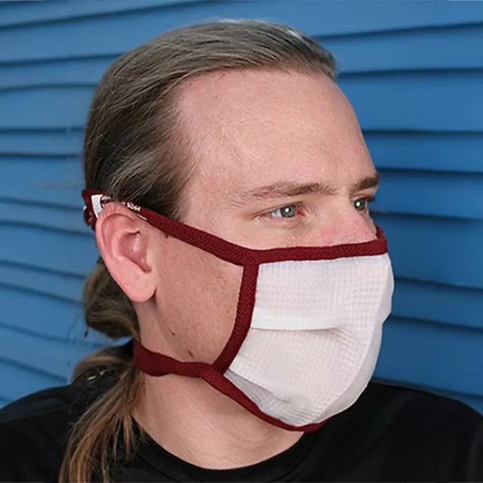 Man wearing a white dust protection mask with red trim, side view, blue background