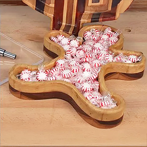 Wooden gingerbread man tray filled with peppermint candies on a workbench