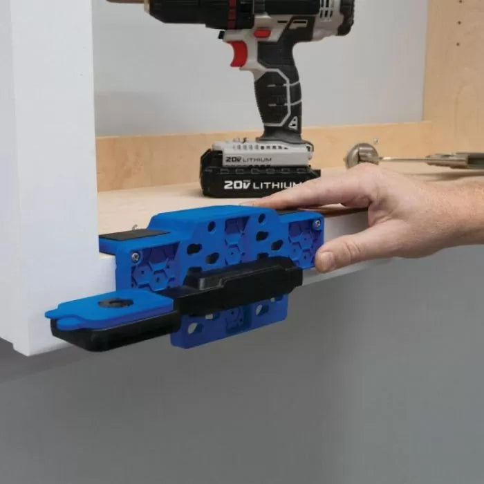 Pocket hole jig clamped to wood board with drill and tools in background, woodworking setup
