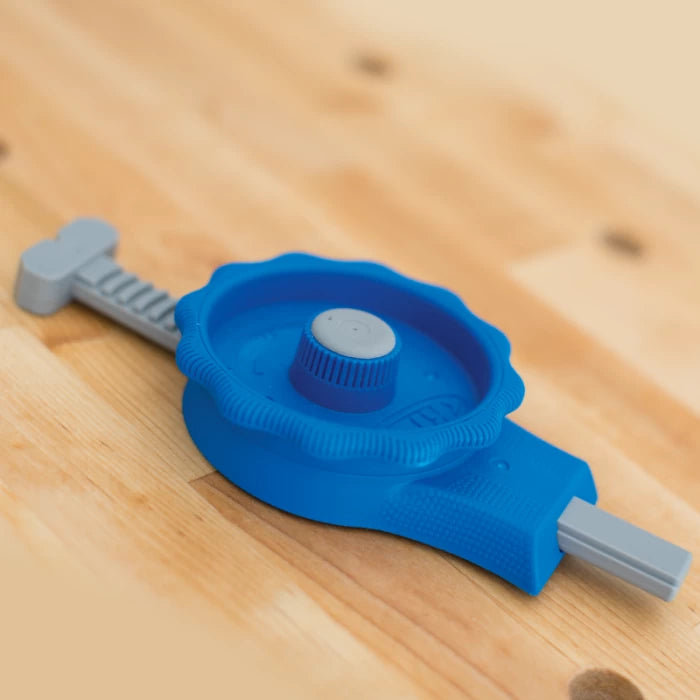 Blue adjustable woodworking stop clamp tool on a wooden workbench.