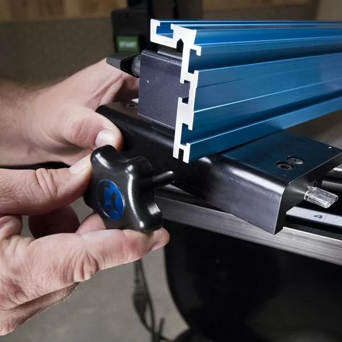 Hands adjusting blue aluminum router table fence with T-track and locking knob