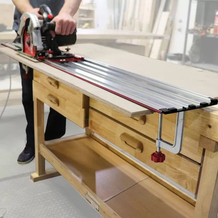 Woodworker using a circular saw with an aluminum track guide clamped to a workbench