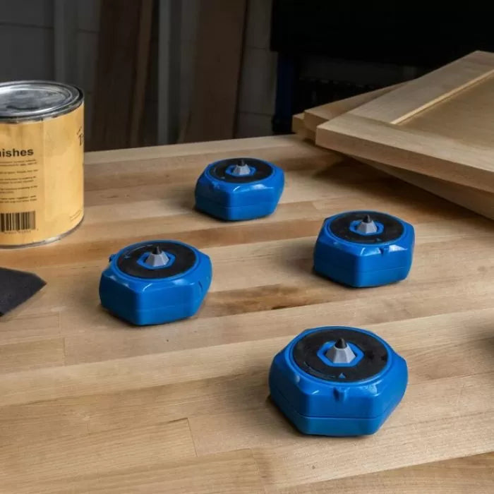 Set of four blue woodworking bench cookies on a workshop table with wood panels and finish can