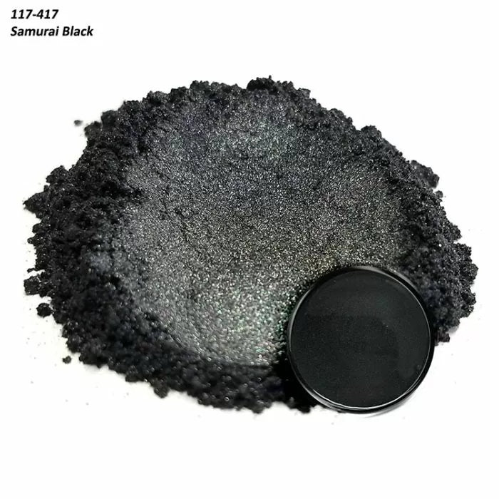 Loose pile of metallic black powder with a round compact labeled Samurai Black
