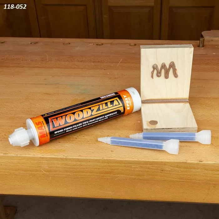 Woodzilla two-part epoxy adhesive tube on workbench with wood joint and mixing nozzles