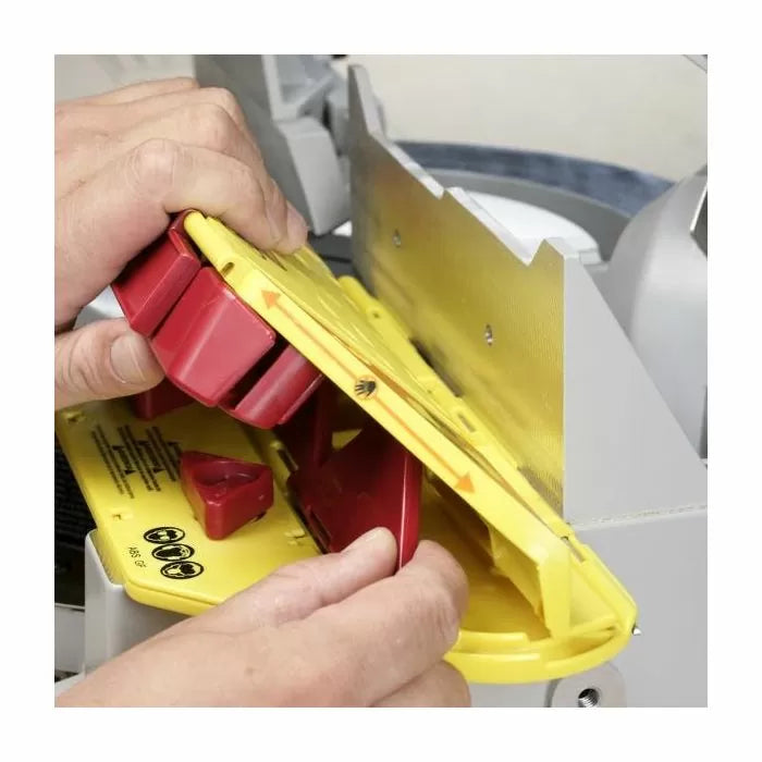 Hand adjusting yellow and red woodworking safety jig on a saw table for precision cuts