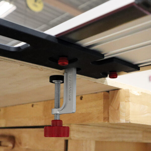 Router table fence clamp with red adjustment knob mounted to woodworking table