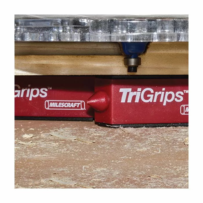 Woodworking router on board supported by red TriGrips bench blocks on a work surface