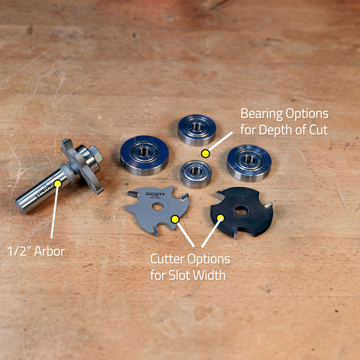 Slot cutter router bit kit with 1/2 inch arbor, various bearings, and cutter blades on workbench.