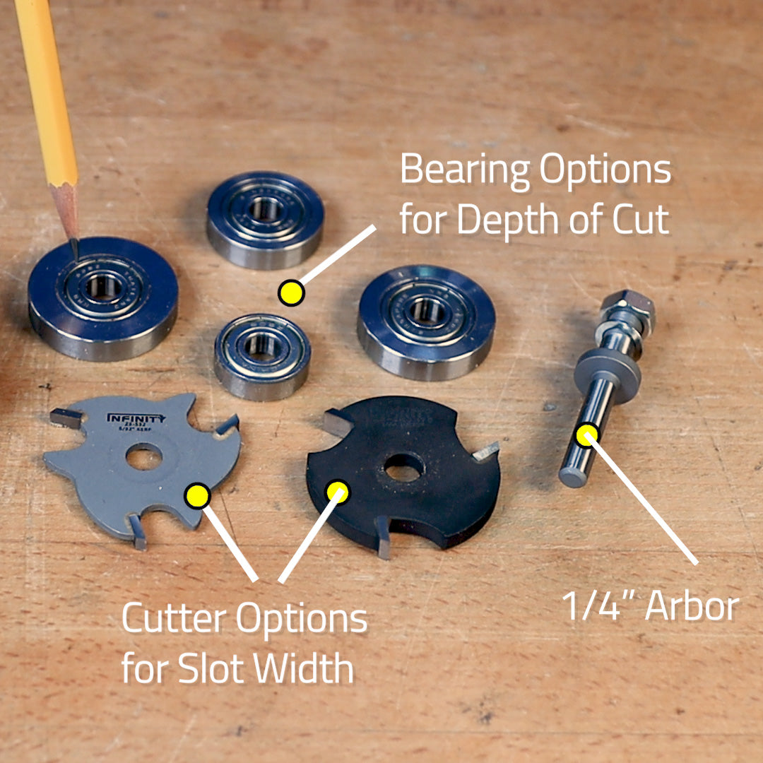 Router slot cutter set with bearings, cutter blades for slot width, and 1/4 inch arbor on workbench.