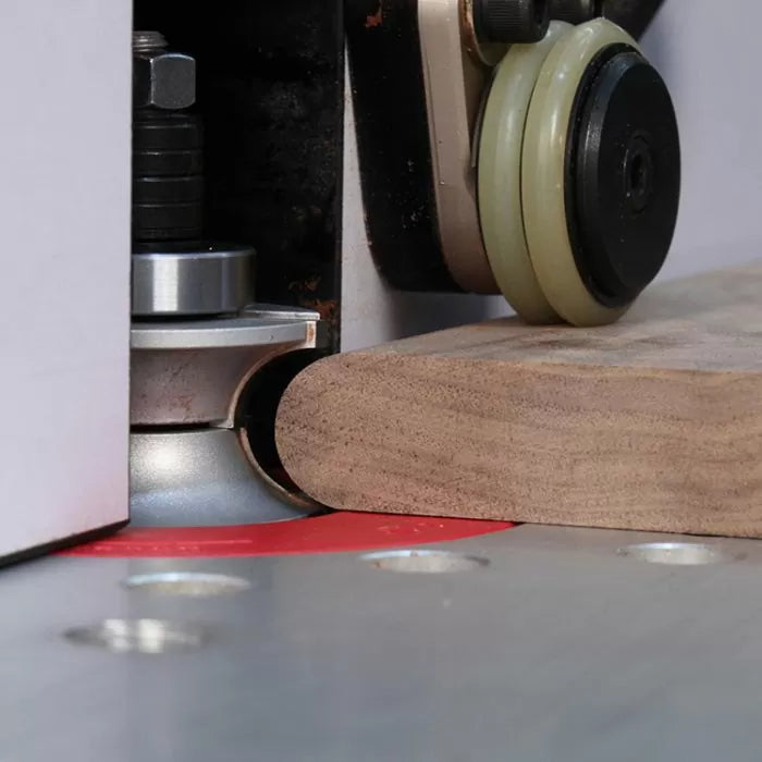 Router bit shaping wood edge on router table with guide bearing and fence