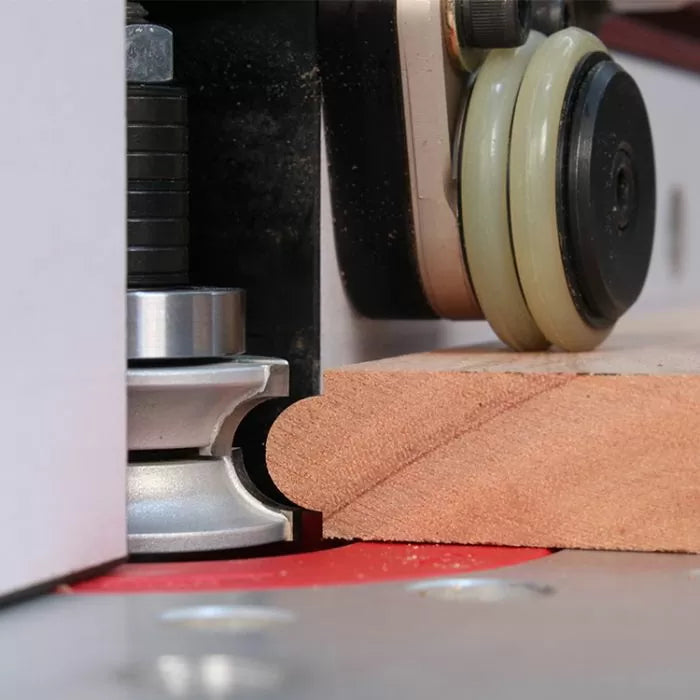 Router bit shaping wooden board edge on woodworking router table