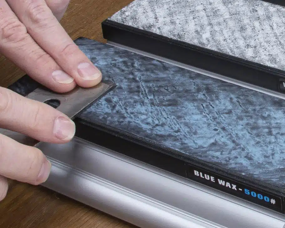 Hand stropping a plane blade on a 5000 grit blue wax honing stone for woodworking tool sharpening