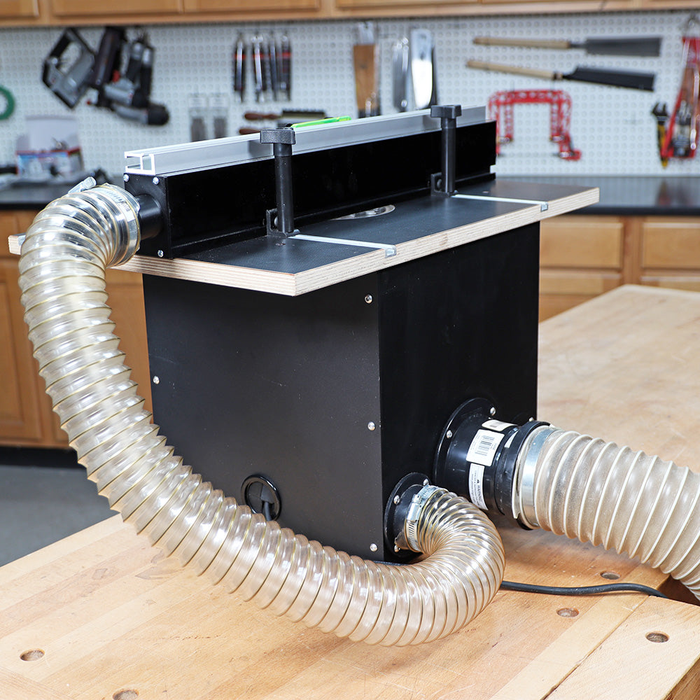 Router table dust collection box with clear flexible hoses in woodworking shop