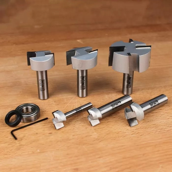 Woodworking router bits set with bearings and hex key on wood surface