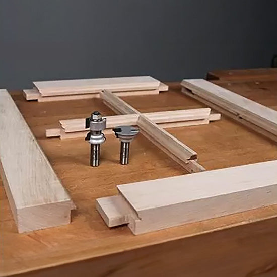 Router bits with wooden frame joinery pieces on a workbench, woodworking tools