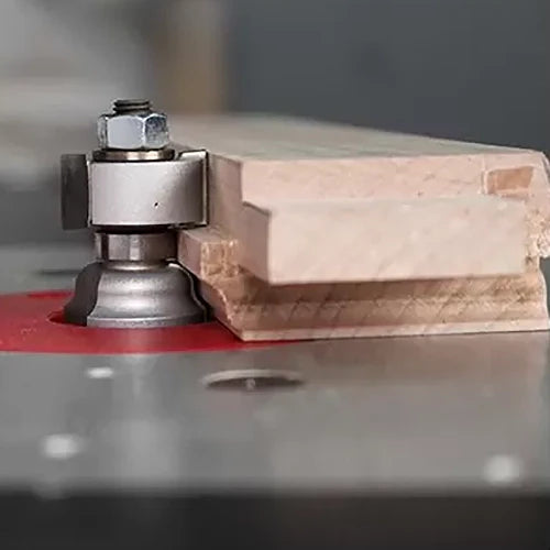 Woodworking router bit shaping wood edge on a router table in workshop setting