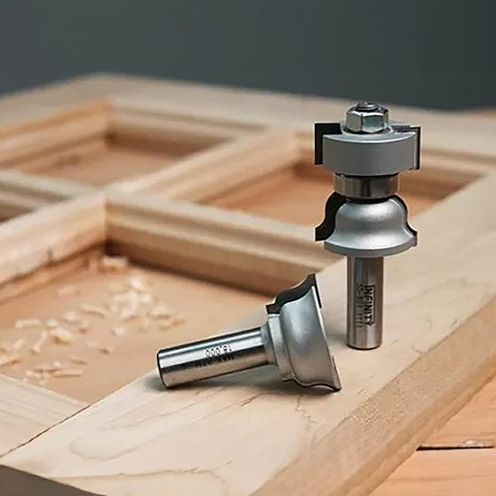 Cabinet door rail and stile router bits set on a wood frame with wood shavings