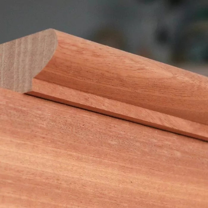 Close-up of crown molding profile cut in hardwood, showing smooth routed edge detail.