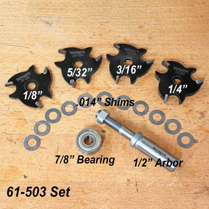 Woodworking slot cutter set with four blades, shims, bearing, and arbor on a wood surface