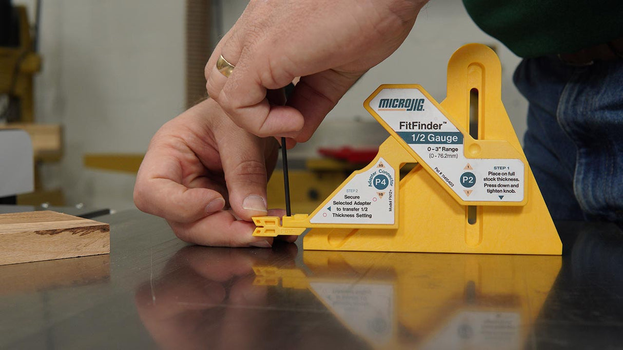 Hand using MicroJig FitFinder 1/2 Gauge woodworking measuring tool on workbench