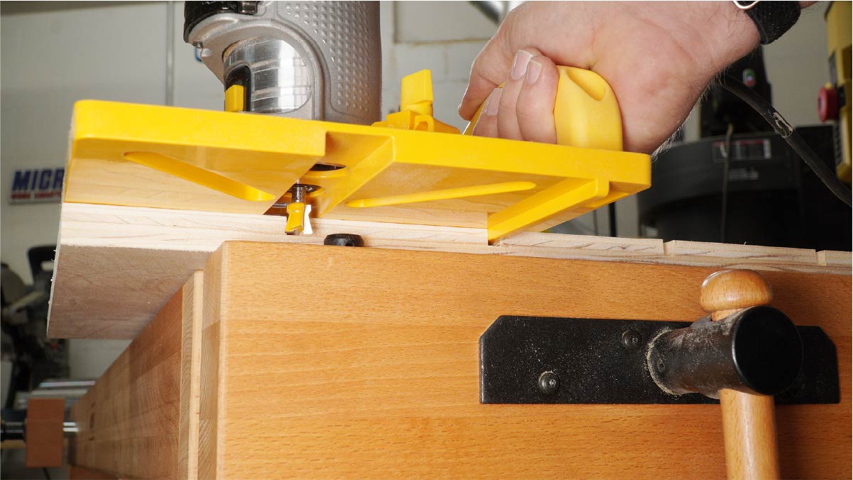 Wood router with yellow guide cutting edge on woodworking bench