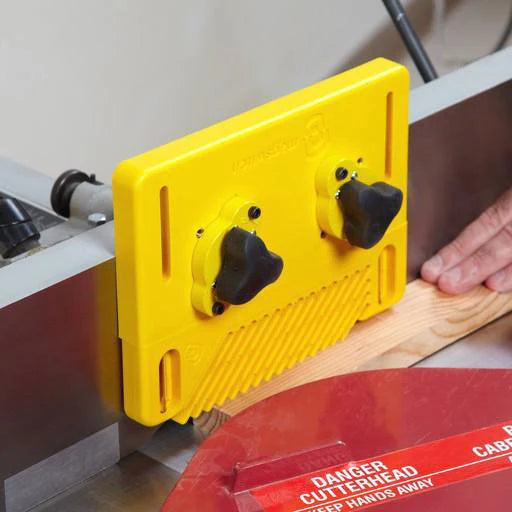 Yellow woodworking push block guiding wood through a jointer for safe, precise cutting