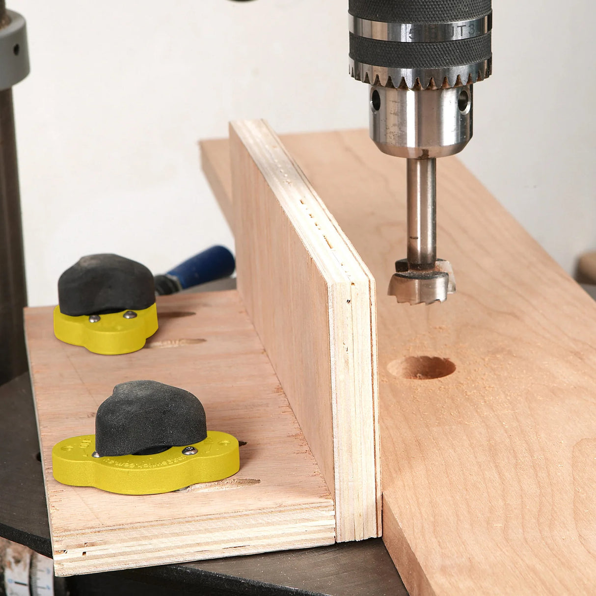 Drill press with Forstner bit making a hole in wood using a woodworking drill press fence jig