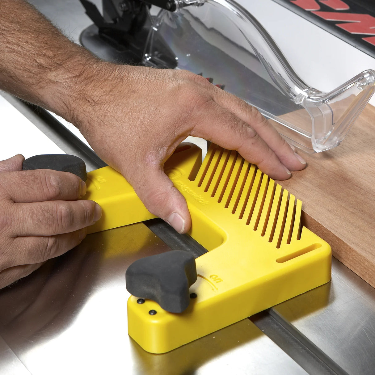 Yellow table saw featherboard holding wood for safe, precise woodworking cut