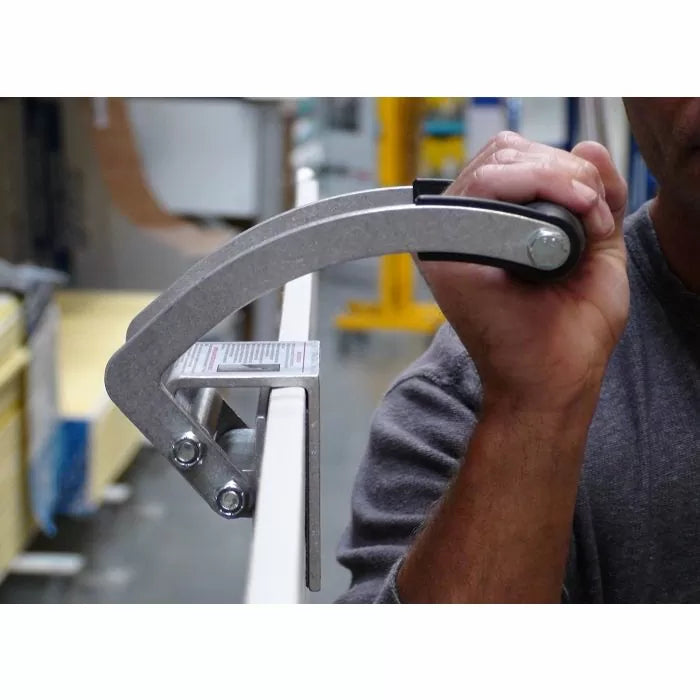 Person using a woodworking edge clamp tool on a board in a workshop setting
