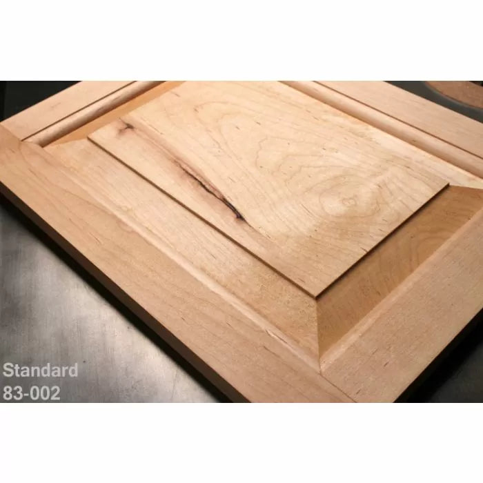 Unfinished wooden cabinet door with beveled raised panel on workshop table