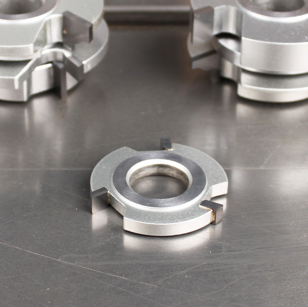 Carbide-tipped woodworking shaper cutter head on a metal surface for precision joinery