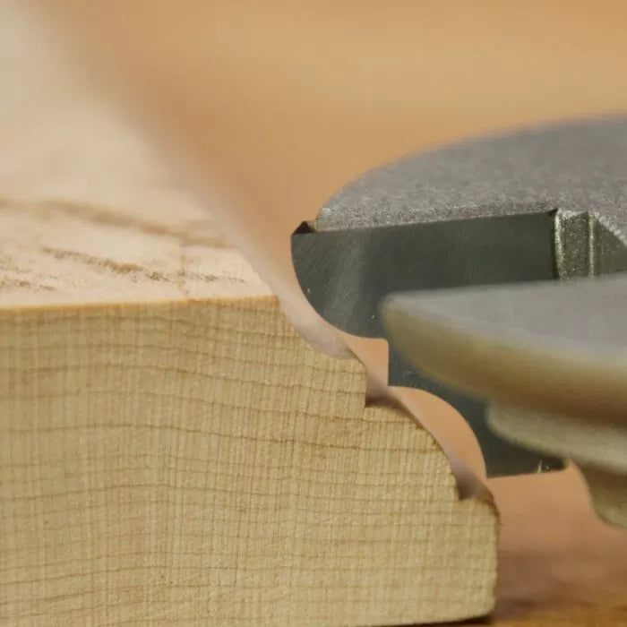 Router bit cutting decorative edging profile on wood close-up