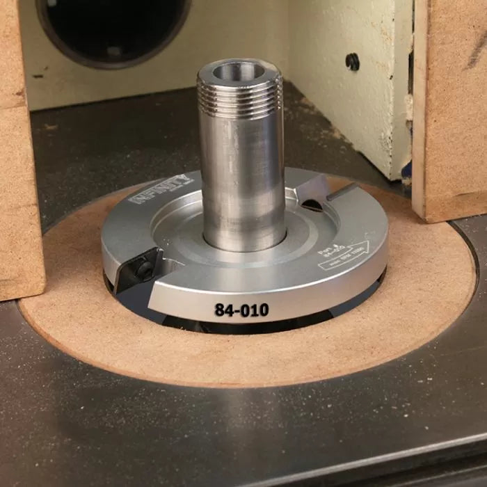 Precision woodworking shaper cutter head mounted on router table with MDF insert.