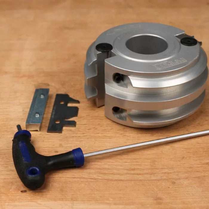 Aluminum woodworking planer cutter head with blades and hex key on wood workbench