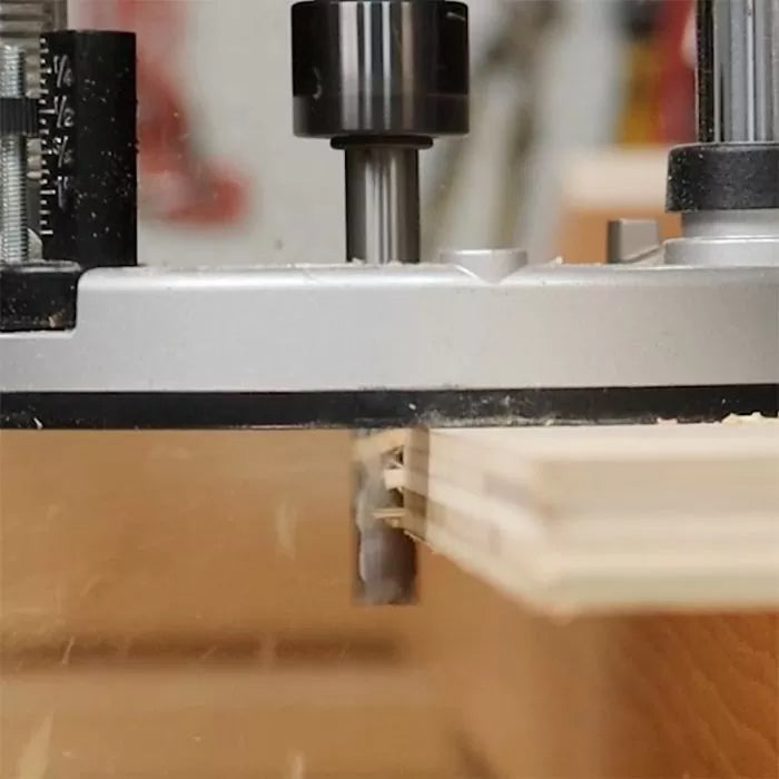 Close-up of router bit cutting dado groove in plywood for woodworking precision.